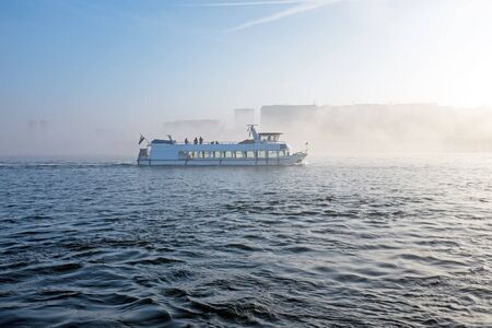 Cruiseboat in the fog in the harbour from Amsterdam in the Netherlandsの写真素材