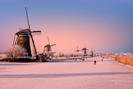 Ice skating at Kinderdijk in the Netherlands at sunsetの写真素材