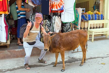 Tourist with a cow in front of a clothing shop in Laxman Jhula Indiaのeditorial素材