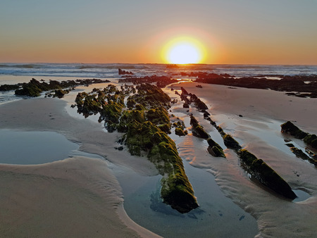 Natural rocks in the water from the atlantic ocean at sunsetの写真素材