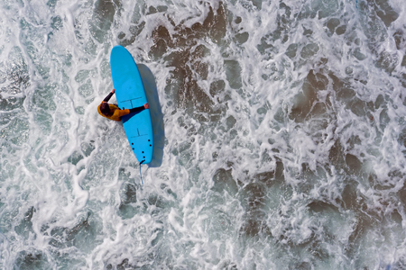 Aerial shot from a surfer going to surf in the oceanの写真素材