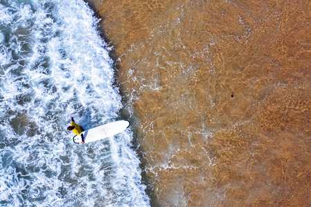 Aerial shot from a surfer going to surf in the oceanの写真素材