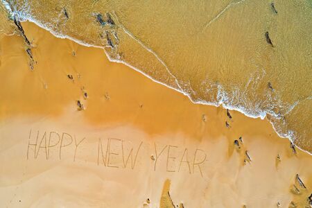 Aerial top shot from ocean waves and handwritten Happy New Year at the beachの写真素材