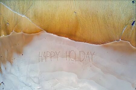 Aerial top shot from ocean waves and handwritten Happy holiday at the beachの写真素材