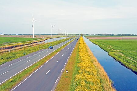Aerial from a typical dutch landscape in the countryside from the Netherlands: straight roads, flat landscape canal and wind turbinesの写真素材