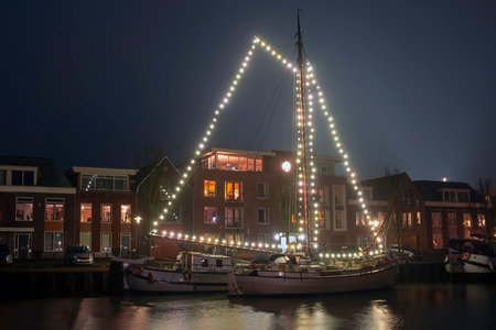 Decorated traditional sailing ship in the harbor from Harlingen in the Netherlands in christmastime...
