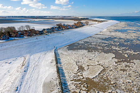 Aerial from snowy village Moddergat in Friesland at a frozen Waddensea in the Netherlands in winter