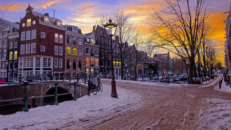 City scenic from a snowy Amsterdm in winter in the Netherlands at sunsetの写真素材