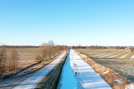 Aerial from ice skaters on a canal in the countryside from the Netherlandsの写真素材