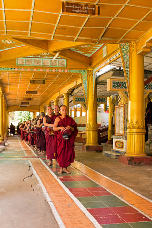 BAGO, MYANMAR - November 26, 2015: Monks waiting in a row to go to the dining room in Kha Khat Waing...
