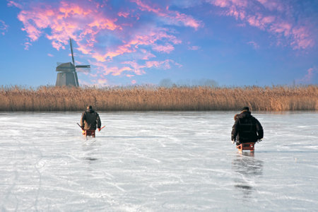Ice sledding on a cold winterday at the windmill in the Netherlands at sunsetの写真素材