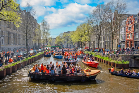 Amsterdam, The Netherlands - April 27, 2023: Locals in orange celebrating Kings Day on the canals in Amsterdam the Netherlandsの写真素材