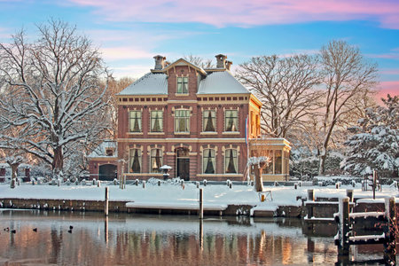Typical snowy Dutch 15th century house in the countryside from the Netherlands in winter at sunsetの写真素材