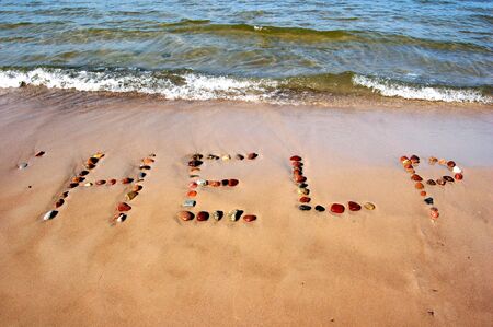 Word HELP on beach sand, made from rocksの写真素材