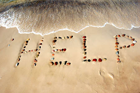 Word HELP on beach sand, made from rocksの写真素材