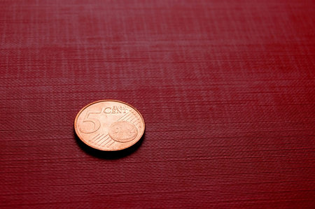 Coin (5 euro cent) on red surface