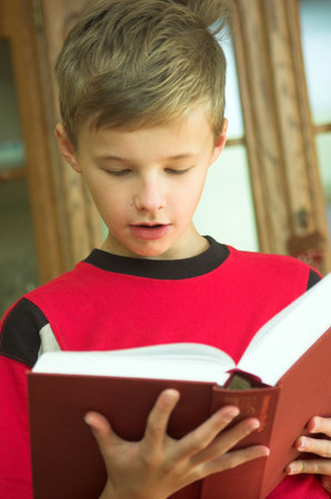 Young boy reading old, heavy book