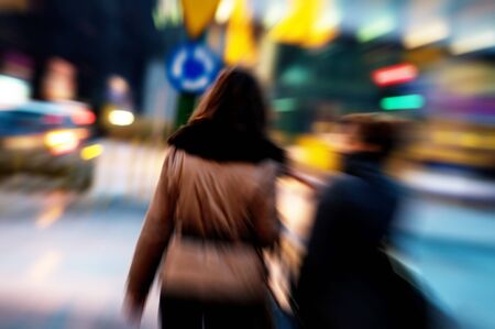 Two attractive women walking in a big city centre at nightの写真素材