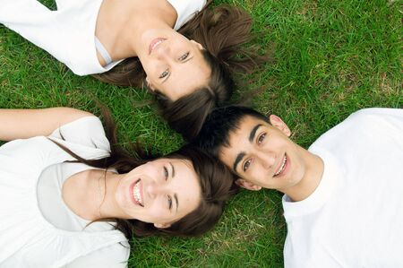 Three young happy friends lying together and laughing. Top viewの写真素材