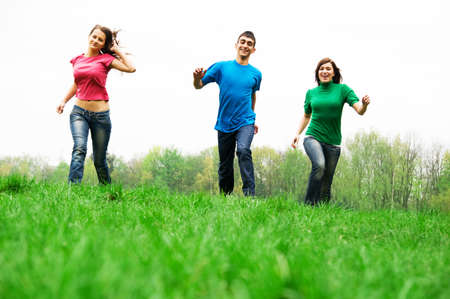 Three happy friends having fun on the spring meadowの写真素材