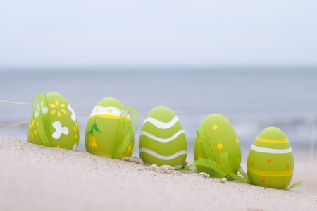 Easter decorated eggs on sand. Beach and ocean in the background Easter decorated eggs on sand. Beach and ocean in the background
