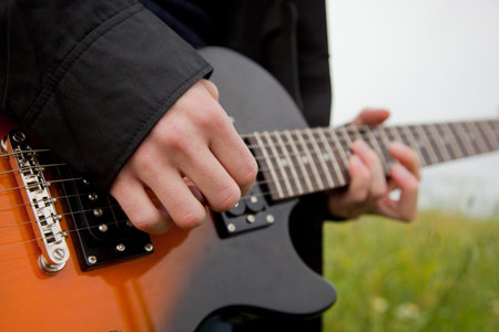 Close up of a man playing guitar outdoors