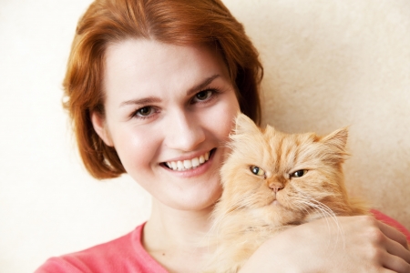 Young woman with Persian cat smiling portraitの写真素材