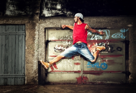 Young man jumping / dancing on grunge graffiti wall backgroundの写真素材