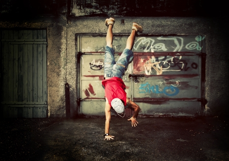 Young man jumping / dancing on grunge graffiti wall backgroundの写真素材