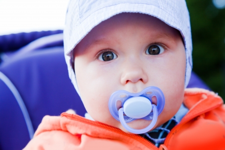 Young baby boy with a dummy in his mouth. Outdoors portraitの写真素材