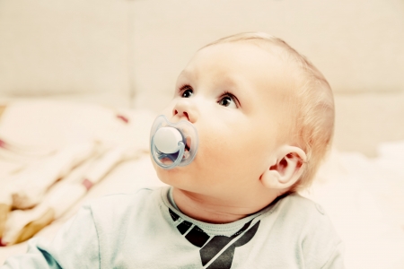 Young baby boy with a dummy in his mouth looking aboveの写真素材