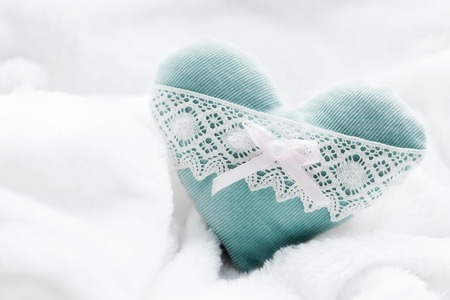 Vintage handmade plush turquoise heart on the soft white blanket. Romantic love, Valentine's Day concepts.の写真素材