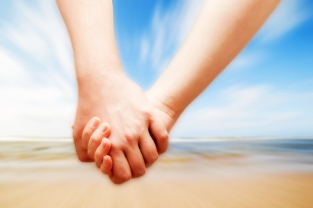 A couple in love hand in hand on the sunny beach. Vacation, romance, happinessの写真素材