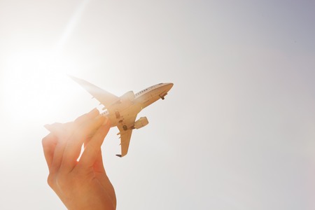 Airplane model in hand on sunny sky. Concepts of travel, transportation, transport, dreaming about holidaysの写真素材