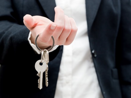 A real estate agent holding keys to a new house in her hands. Real estate industryの写真素材