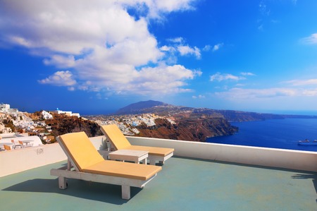 Two deckchairs on the roof of the building on Santorini island, Greece. View on Caldera and Aegean sea, sunny day, blue sky.の写真素材