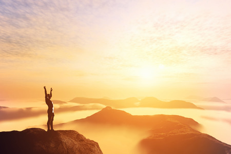 Happy man with hands up on the top of the world, above clouds and mountains. Success, winner, bright future