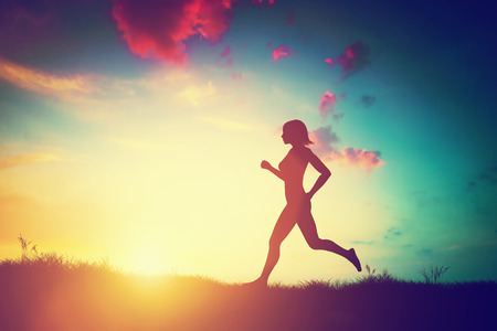 Silhouette of a fit woman running at sunset. Training, jogging, healthy lifestyle.