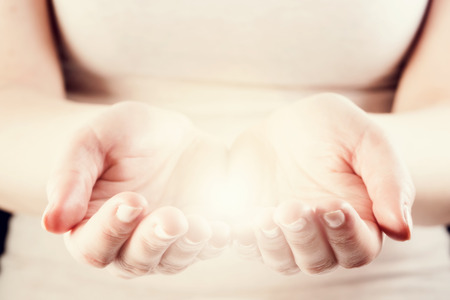 Light in woman hands in cupped shape. Giving, share, protect, care, energy concept.の写真素材