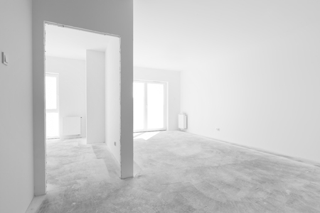 Empty new apartment rooms for interior arrangement. Light from the windows, white walls, concrete floorの写真素材