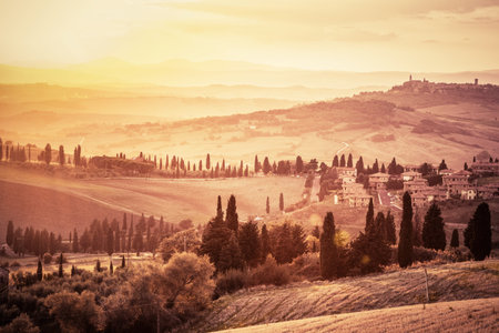 Wonderful Tuscany countryside landscape with cypress trees, farms and small medieval towns, Italy. Vintage sunset