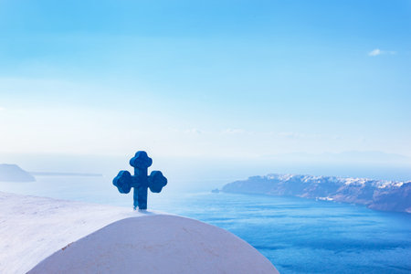 Blue cross on the church roof in Fira on Santorini island, Greece. Caldera view, Aegean sea.