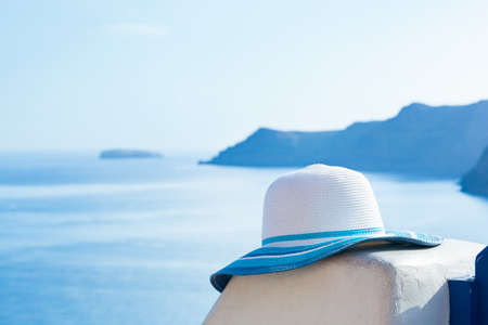 Sun hat on white stone wall on Santorini island, Greece. View on Caldera and Aegean sea from Oia. Travel, tourist, tourism conceptの写真素材