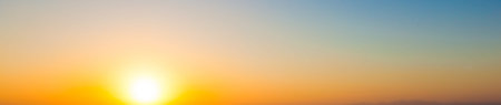 Wide panorama sunset background. Clear sky with setting sun and warm gradient colors