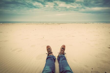 First person perspective of man legs in jeans on the autumn beach. Vintage, retro styleの写真素材