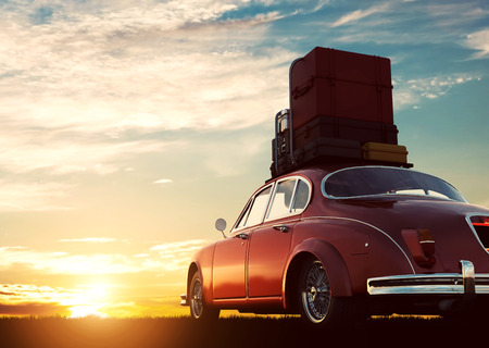 Retro red car with luggage on roof rack at sunset. Travel, vacation concepts. 3D illustrationの写真素材