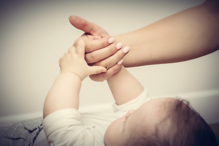 Parenthood. Mother and her little baby touching each other hands. Maternity love concept. Vintageの写真素材