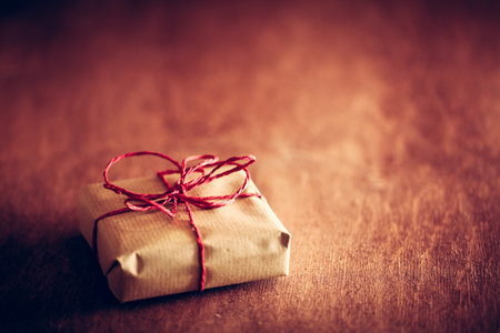 Rustic retro gift, present box with red ribbon. Christmas time, vintage mood. Handmade eco paper...