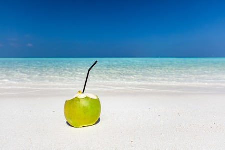 Fresh green coconut with pipe inside, ready to drink. Tropical beach in Maldives, Indian Oceanの写真素材