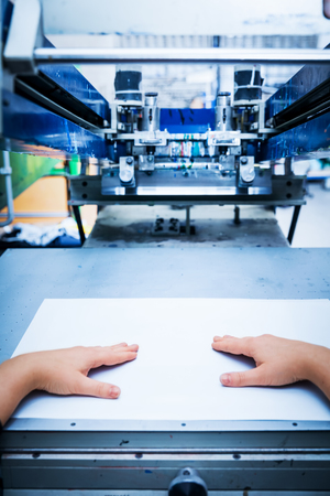Worker preparing print screening metal machine. Industrial printer. Manufacture work. First person perspective.の写真素材